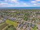 An aerial view featuring neighborhood homes, lush green trees, pond, and a blue sky backdrop at 879 De Soto Blvd, Tarpon Springs, FL 34689