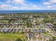 An aerial showing neighborhood homes, lush trees, pond, and open green space with a blue sky at 879 De Soto Blvd, Tarpon Springs, FL 34689