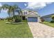Charming two-story home featuring a blue garage door, lush green lawn, and beautifully landscaped front yard with vibrant flowers at 879 De Soto Blvd, Tarpon Springs, FL 34689
