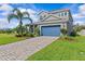 Attractive two-story home featuring a paved driveway, lush landscaping, and a blue garage door at 879 De Soto Blvd, Tarpon Springs, FL 34689