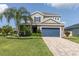 Inviting two-story home with a blue garage door, lush lawn, and well-manicured landscaping, creating great curb appeal at 879 De Soto Blvd, Tarpon Springs, FL 34689