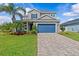 Charming two-story home with a manicured lawn, stone driveway, and vibrant blue garage door at 879 De Soto Blvd, Tarpon Springs, FL 34689