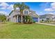 Beautiful two-story home with a well-maintained lawn, lush landscaping, and a blue garage door at 879 De Soto Blvd, Tarpon Springs, FL 34689