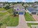 Two-story home featuring manicured landscaping and a brick driveway leading to a blue garage door at 879 De Soto Blvd, Tarpon Springs, FL 34689