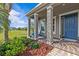 Inviting front porch with columns, a blue front door, and well-maintained landscaping at 879 De Soto Blvd, Tarpon Springs, FL 34689