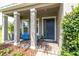 Welcoming front porch with columns and a blue front door with updated landscaping at 879 De Soto Blvd, Tarpon Springs, FL 34689