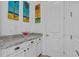 Convenient wet bar with granite countertop, white cabinets, and tropical artwork at 879 De Soto Blvd, Tarpon Springs, FL 34689