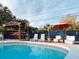 The pool area features a Tiki bar, chaise lounges, an umbrella-covered table, and lush landscaping at 9201 86Th Ave, Seminole, FL 33777