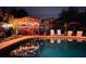 Backyard pool and outdoor lounge area with lighting, seating, and a tiki bar, perfect for evening enjoyment at 9201 86Th Ave, Seminole, FL 33777
