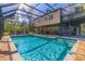 Enclosed pool features travertine tile deck, outdoor seating, plus view of the home's exterior and wooded backyard at 9298 Carr Rd, Riverview, FL 33569