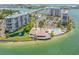 Aerial view of condos featuring a pond with fountain, community pool, tennis courts, and bay access with boat docks at 9495 Blind Pass Rd # 406, St Pete Beach, FL 33706