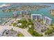 Aerial view of waterfront condos featuring bay access, tennis courts, pool, boat docks, and manicured landscaping at 9495 Blind Pass Rd # 406, St Pete Beach, FL 33706