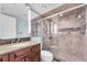 Beautiful bathroom features dark wood vanity with granite, glass-enclosed shower with tiled walls and a hand rail at 9495 Blind Pass Rd # 406, St Pete Beach, FL 33706