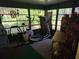 Bright sun room featuring exercise equipment and large windows overlooking a lush green yard at 12231 Fort King Rd, Dade City, FL 33525