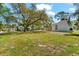 Spacious backyard with an oversized lawn, privacy fence, and mature trees offering ample shade at 1232 Sedeeva S Cir, Clearwater, FL 33755