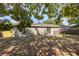 Exterior view of a home's fenced back yard with mature trees and a cement patio at 12597 Cumberland Dr, Largo, FL 33773