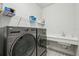 Laundry room featuring gray washer and dryer, white countertops and sink, and decorative tile flooring at 13460 Bergamont Cir, Tampa, FL 33618