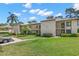 A two-story condo building showcasing a lush green lawn, palm trees, and a beige exterior on a sunny day at 135 Nina Way # 35, Oldsmar, FL 34677