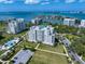 Aerial view of condo buildings, a sparkling pool, and manicured grounds, highlighting the community's amenities and waterfront views at 145 Belleview Blvd # 201, Belleair, FL 33756