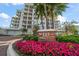 Luxury condo building exterior with blooming flowers and lush palm trees, enhancing the entrance appeal at 145 Belleview Blvd # 201, Belleair, FL 33756