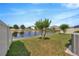 Spacious backyard with a view of the pond, featuring green grass and a white fence at 1476 Fort Cobb Ter, Wesley Chapel, FL 33543