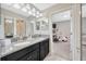 Well-lit bathroom with dual sinks, dark cabinetry, and an adjacent room, all beautifully designed at 1476 Fort Cobb Ter, Wesley Chapel, FL 33543