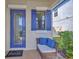 Cozy entryway with a decorative blue door, shutters, and a wicker chair at 1476 Fort Cobb Ter, Wesley Chapel, FL 33543