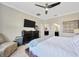 Spacious main bedroom featuring a ceiling fan, TV, dresser, accent chair, and ensuite bathroom access at 1476 Fort Cobb Ter, Wesley Chapel, FL 33543