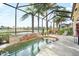 Relaxing screened-in pool with a stone accent wall and views of the serene lake and palm trees beyond at 15707 Crystal Waters Dr, Wimauma, FL 33598