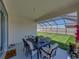 A covered patio with a dining table set and an expansive view of the grassy backyard at 17403 Holly Well Ave, Wimauma, FL 33598