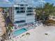 Aerial view of condo featuring a pool, sun loungers, and beachfront access to white sand and blue water at 19816 Gulf Blvd # 602, Indian Shores, FL 33785