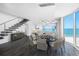 A modern dining room with stylish lighting, a large window with an ocean view, and a staircase at 19816 Gulf Blvd # 602, Indian Shores, FL 33785