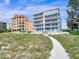 Exterior of luxury apartments next to beach access path featuring ocean views from multiple balconies at 19816 Gulf Blvd # 602, Indian Shores, FL 33785