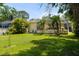 Backyard view featuring green grass, mature trees, and the rear of the home with screened-in porch at 209 Arlington E Ave, Oldsmar, FL 34677