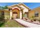 Charming home entrance with lush garden, brick walkway, and arched doorway at 209 Arlington E Ave, Oldsmar, FL 34677