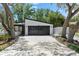 Modern home featuring a large two-car garage with black doors and a long driveway, surrounded by mature trees at 2257 Lake Dr, Dunedin, FL 34698