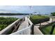 Dock with a wooden walkway leading to a boat lift on the water, framed by lush green bushes and a chain link fence at 3302 W Shell Point Rd, Ruskin, FL 33570
