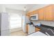 Kitchen featuring light cabinetry, white appliances, and a large window for natural light at 3777 Mission Ct, Largo, FL 33771