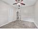 Bedroom with gray carpet, ceiling fan, closet, and doorway to the adjacent bathroom at 4527 24Th S Ave, St Petersburg, FL 33711