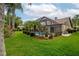 Expansive backyard featuring green lawns, palm trees, and a screened pool area at 5519 Greyston St, Palm Harbor, FL 34685