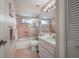 Bathroom featuring shower-tub combination, single sink vanity, pink tile and white cabinets at 5519 Greyston St, Palm Harbor, FL 34685