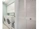 Functional laundry room with white washer, dryer, cabinets, and louvered doors for storage at 5519 Greyston St, Palm Harbor, FL 34685