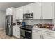 Modern kitchen with stainless steel appliances, quartz countertops, and sleek white cabinetry at 6406 Sanctuary Creek Ln, Tampa, FL 33625