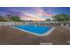 Community swimming pool surrounded by a white fence and lounge chairs; perfect for relaxing on warm days under a colorful sky at 6490 Cape Hatteras Ne Way # 4, St Petersburg, FL 33702