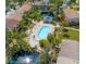 Aerial view of a pool and a covered structure surrounded by manicured landscape and a pond at 7647 Navigator Ct, Port Richey, FL 34668