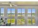 Enclosed sunroom has large windows overlooking outdoor area, plus fan, and a collection of plants at 9450 Harbor Greens Way # 403, Seminole, FL 33776