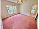Cozy bedroom with pink carpet, a ceiling fan, and a window offering natural light and outdoor views at 10206 Lakeview Dr, New Port Richey, FL 34654