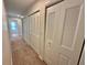 Hallway featuring multiple closet doors, neutral carpet, and a glimpse of natural light at the end at 10206 Lakeview Dr, New Port Richey, FL 34654
