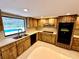 Light and bright kitchen area with wood cabinets and black appliances adjacent to carpeted living area at 10206 Lakeview Dr, New Port Richey, FL 34654