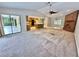 Open-concept living room includes brick fireplace, ceiling fan, neutral carpet, and sliding door access to the patio at 10206 Lakeview Dr, New Port Richey, FL 34654